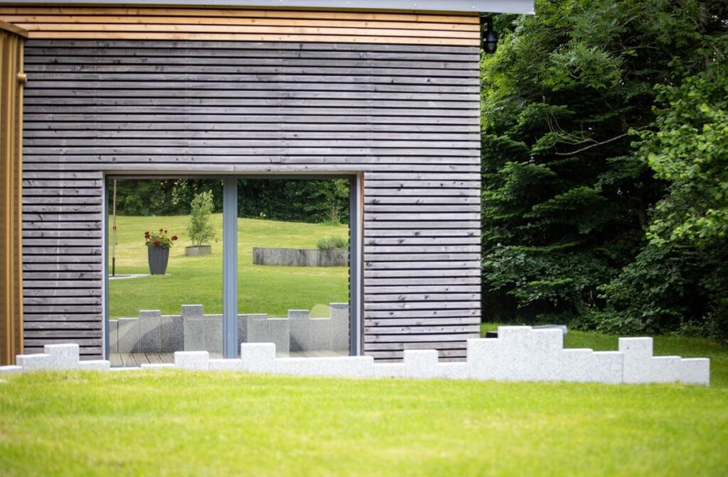 Notre Gîte de luxe dans le Jura avec en mars 2026 façade et verdure